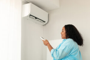 Home black lady turning on ac with remote controller at home